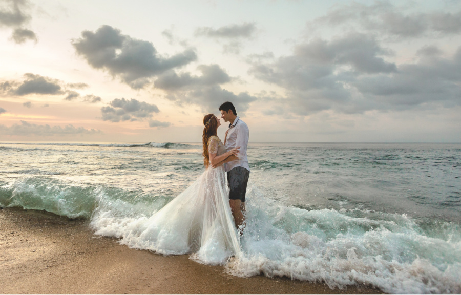 newly married couple standing in the ocean waves