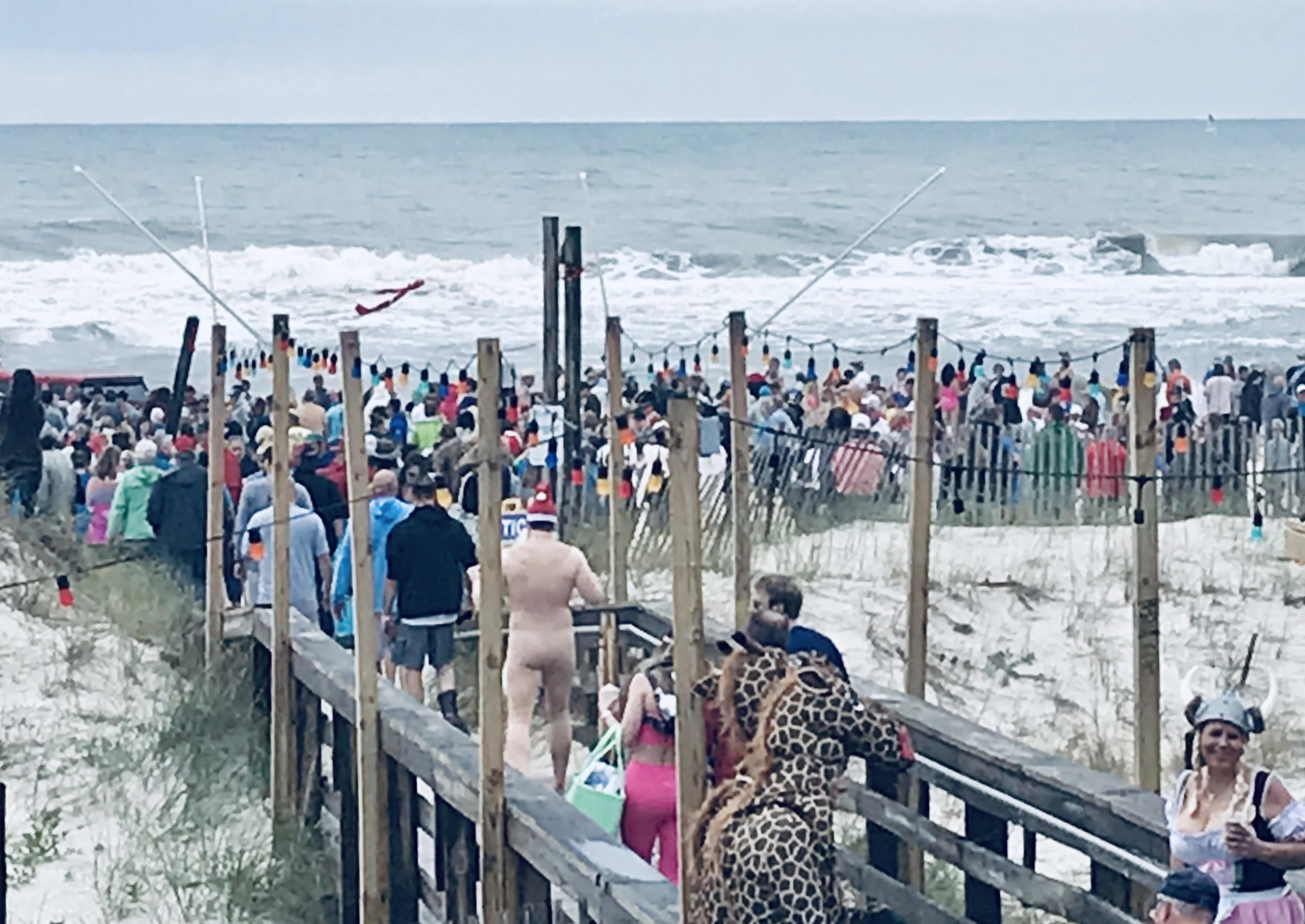 Hundreds of partiers cross the boardwalk and spill onto the beach by Flora-Bama for the 2023 Polar Bear Dip
