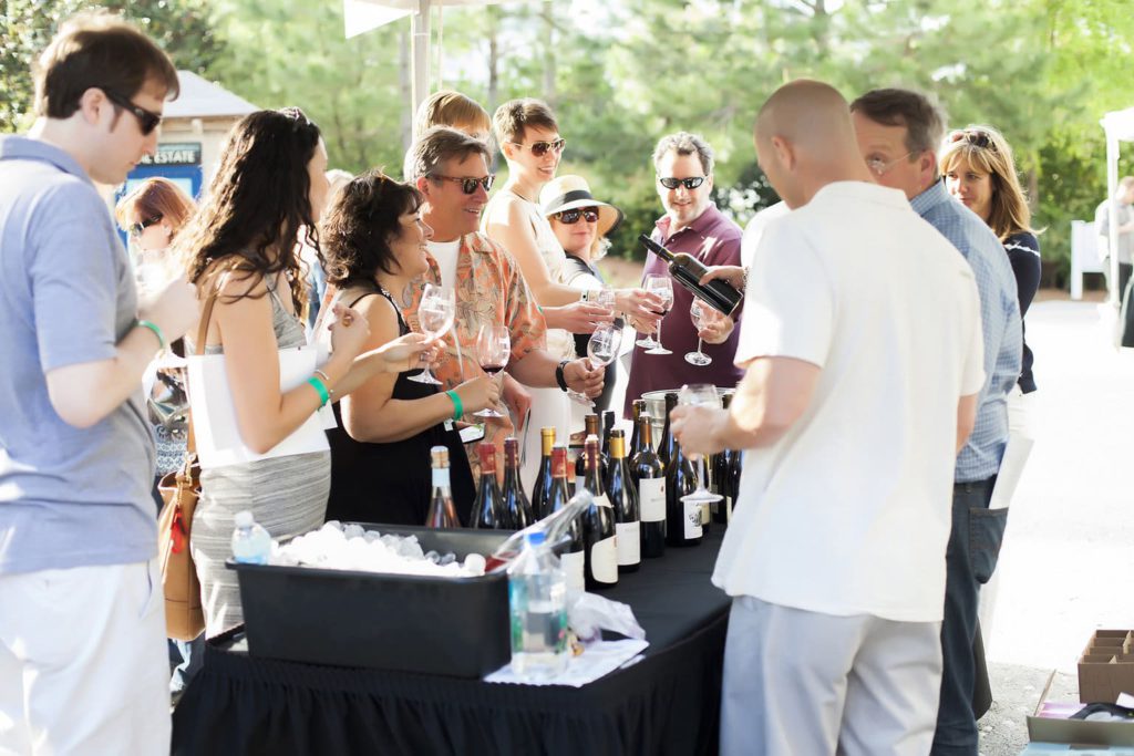 Sandestin Wine Festival attendees hold out wine glasses to be filled by wine makers.