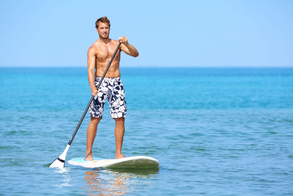 Man stand up paddleboarding on blue water