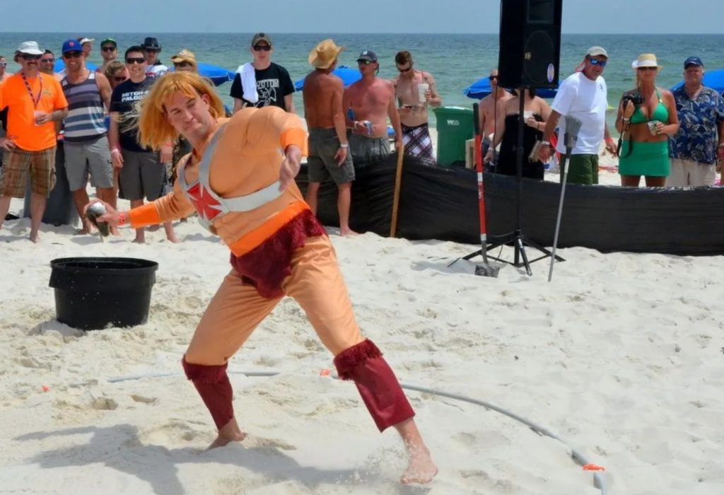 A man in an orange costume and wig about to toss a mullet.